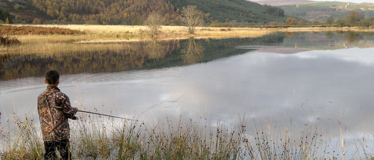 A boy fishing in a river in the Scottish Highlands