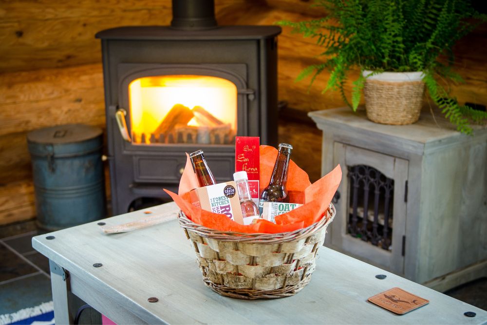An Eagle Brae hamper on the coffee table infront of a log burning fire. 