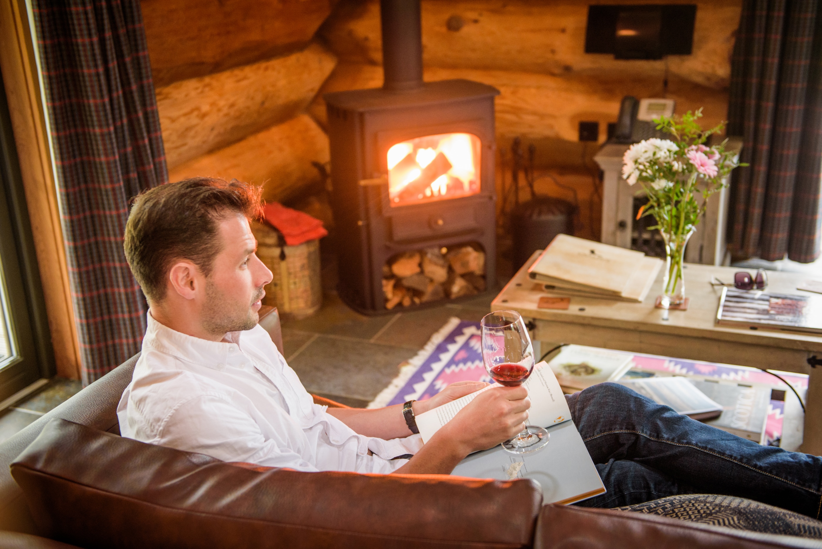 Man relaxing with a glass of wine in front of wood burner