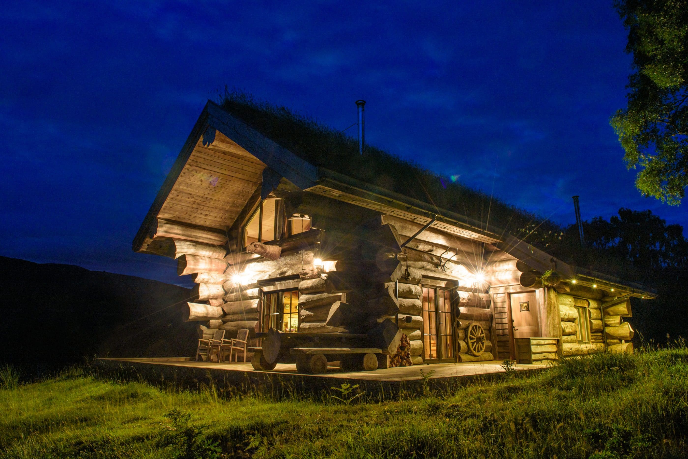 Stunning log cabin lit up at night at Eagle Brae