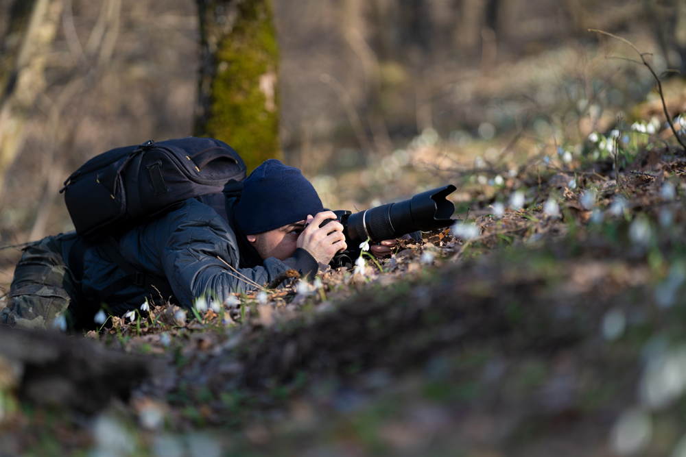 Photographer crawling on the ground to get a nature photo