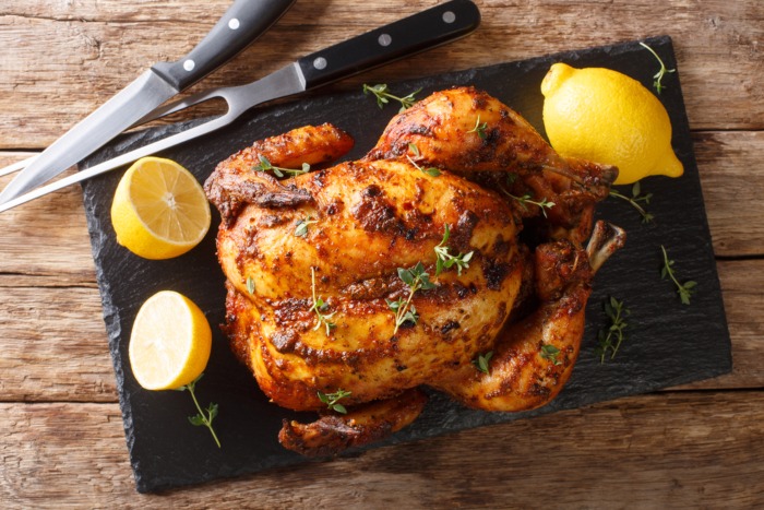 A roast chicken sitting on a board ready to carve