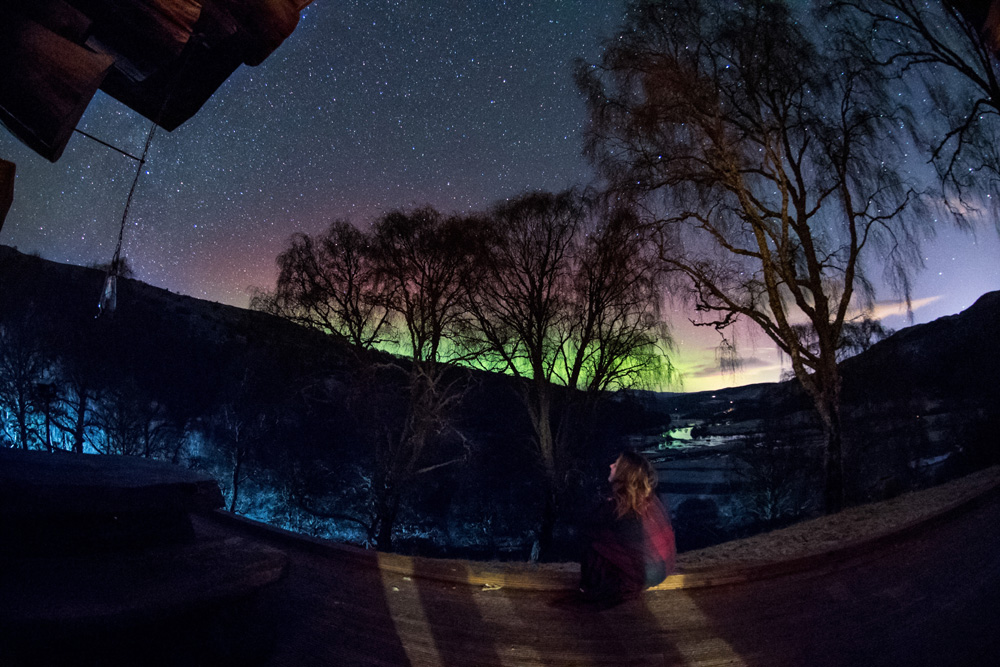 Woman sitting on cabin deck looking up at the stars