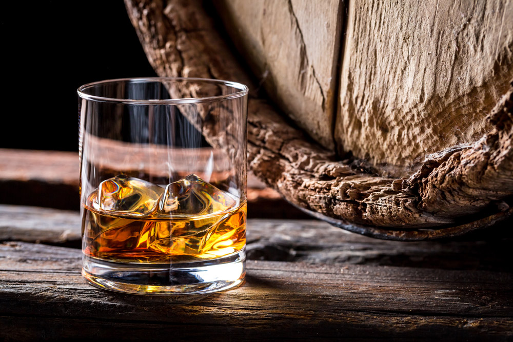 Glass of whisky next to a barrel