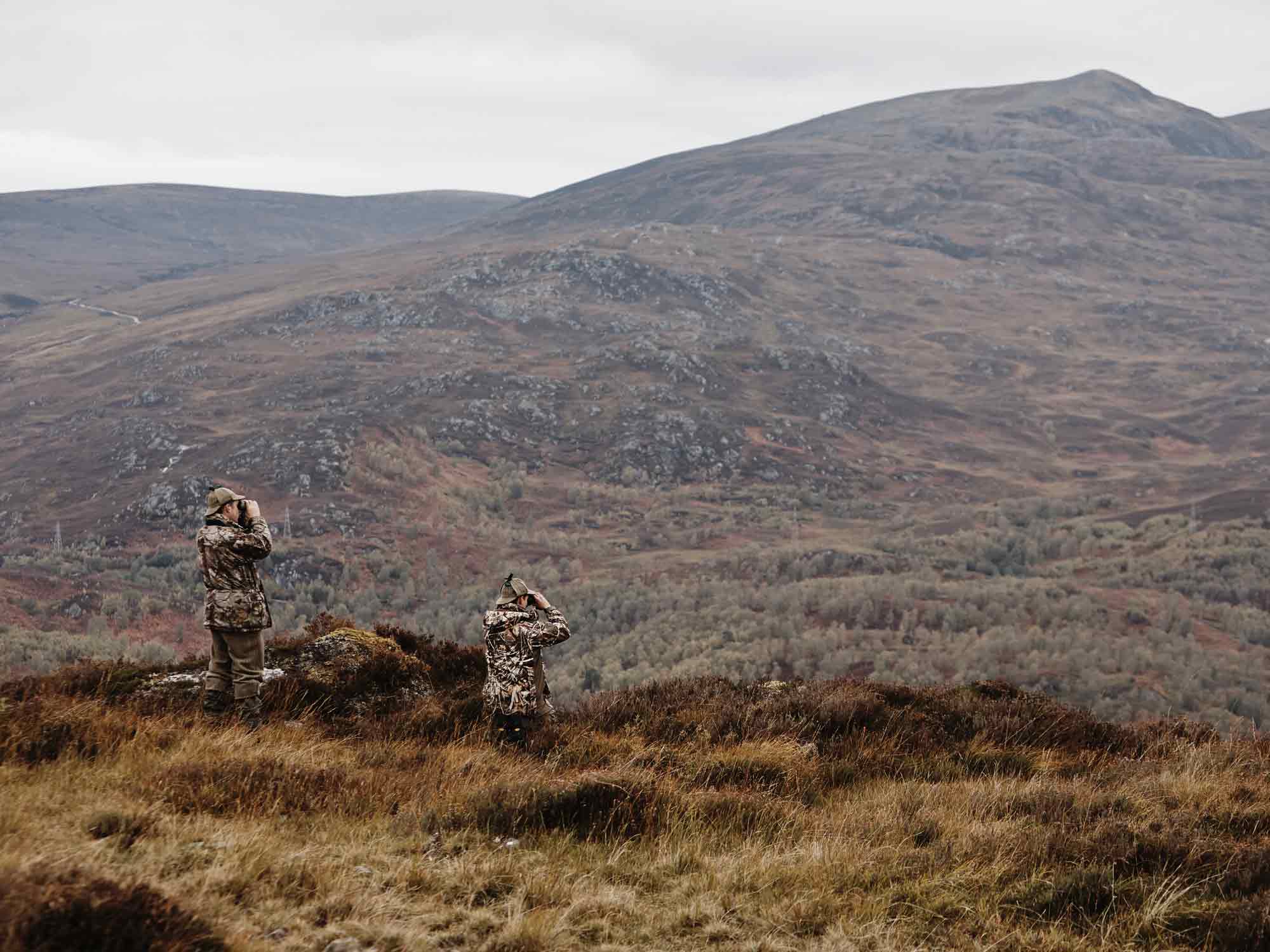 Two men with binoculars in the Scottish Highlands