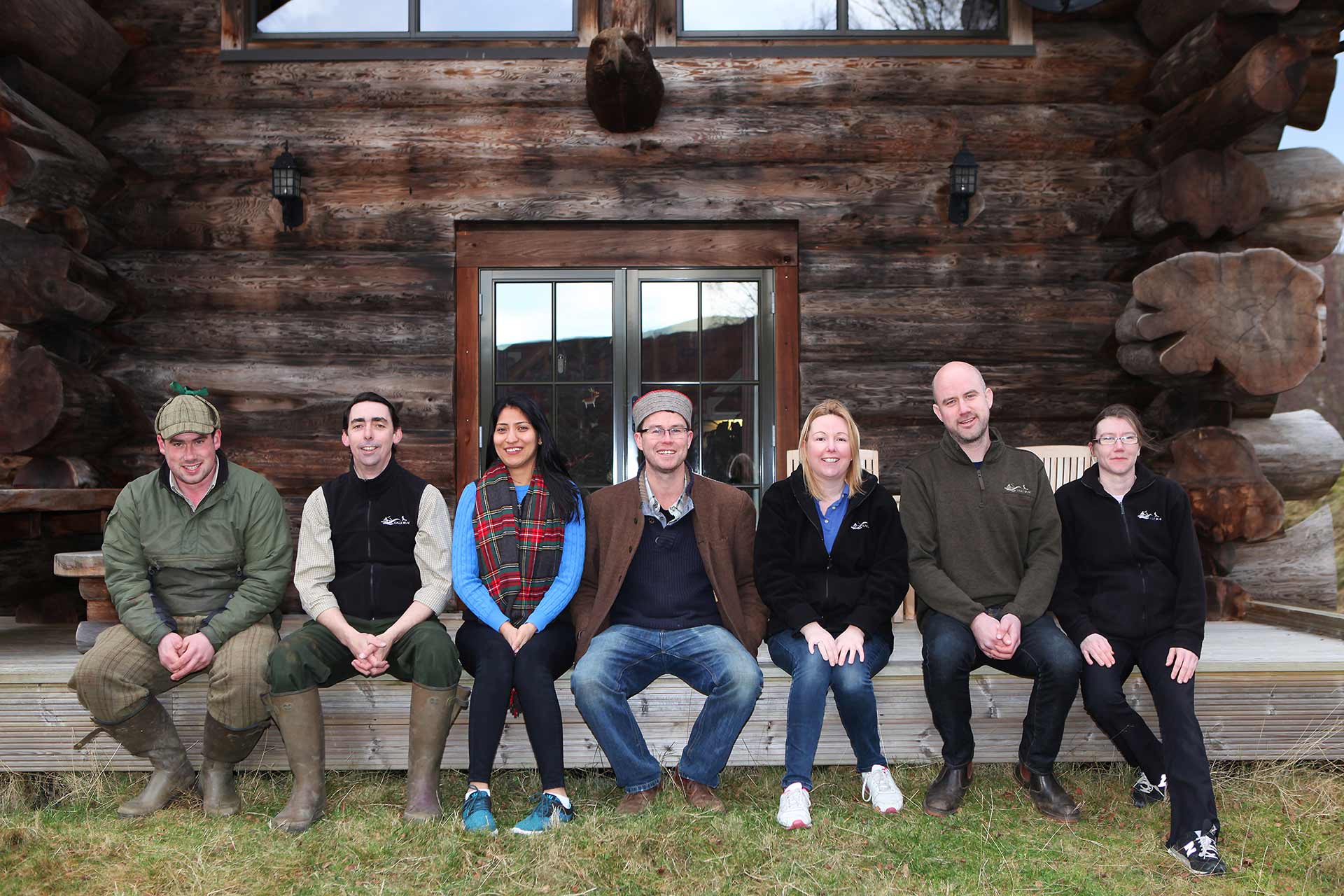 Eagle Brae team sat outside a log cabin