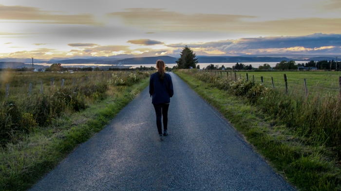 Woman walking along road Beauly Scotland