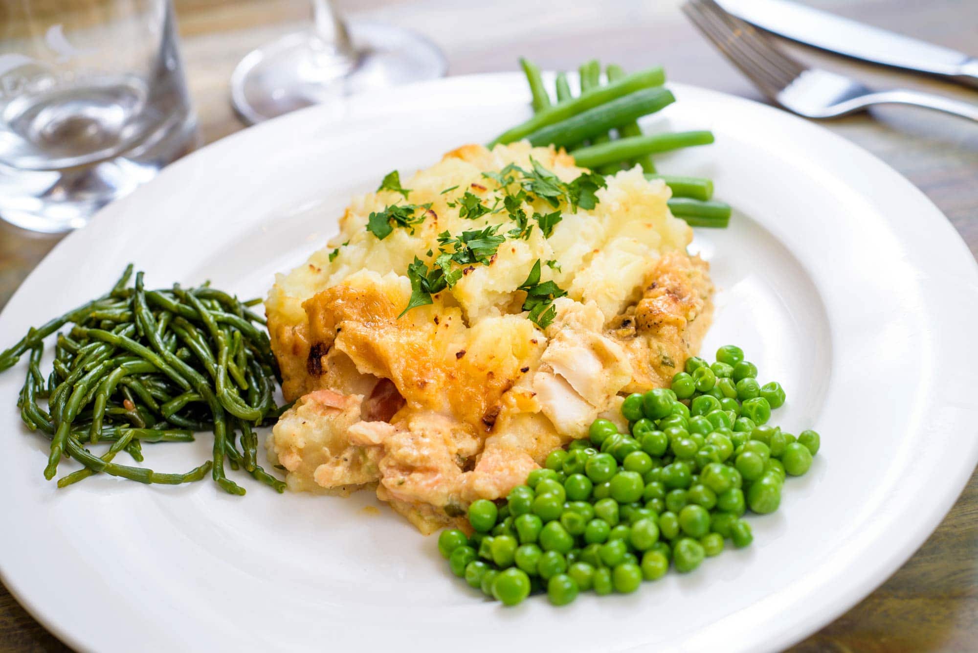 Fish pie served with vegetables on a white plate
